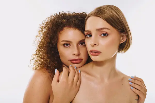 A stunning lesbian couple embraces each other, highlighting beauty and authenticity in a warm studio. — Stock Photo