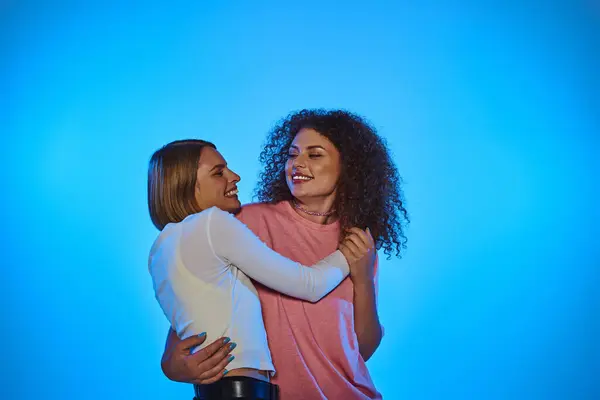 Una coppia gioiosa si abbraccia, irradiando amore su uno sfondo rosa vibrante. — Foto stock