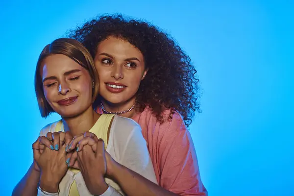 Due gioiose donne lgbt mostrano il loro amore e unità in un ambiente colorato studio, irradiando felicità insieme. — Foto stock