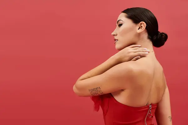 A stunning young woman displays her grace in a striking red dress, radiating elegance and poise. — Stock Photo