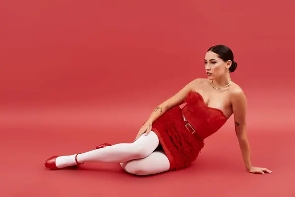 The elegant woman rests on a bold backdrop, showcasing her striking outfit and confident pose. — Stock Photo