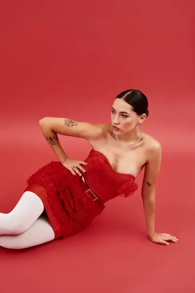 This stunning woman captivates with her pose against a striking red backdrop, showcasing her style. — Stock Photo