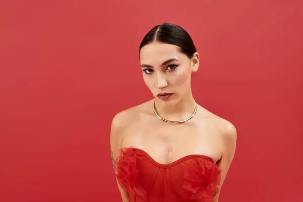 A stunning young woman showcases her beauty in a vibrant red ensemble while posing confidently. - foto de stock