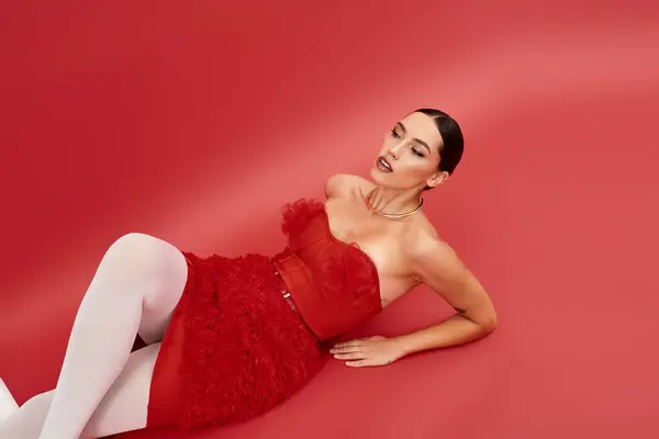 Una hermosa mujer joven descansa elegantemente en un vestido rojo llamativo, mostrando su estilo. — Stock Photo