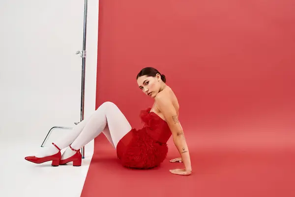 Une jeune femme élégante met en valeur un ensemble rouge vibrant tout en posant de façon réfléchie. — Photo de stock
