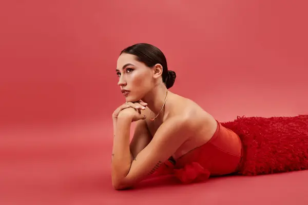 The beautiful woman rests on her elbows, showcasing elegance and confidence in vibrant red attire. — Stock Photo