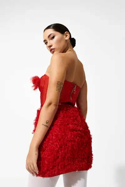 An elegant young woman exudes confidence while modeling a striking red dress with intricate details. — Stock Photo
