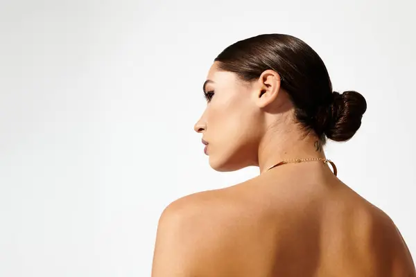 A young woman turns her head slightly, presenting a graceful profile and a chic hairstyle — Stock Photo