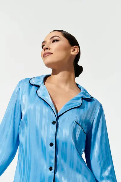 A young woman showcases her elegance wearing chic blue sleepwear, radiating confidence and poise. — Stock Photo