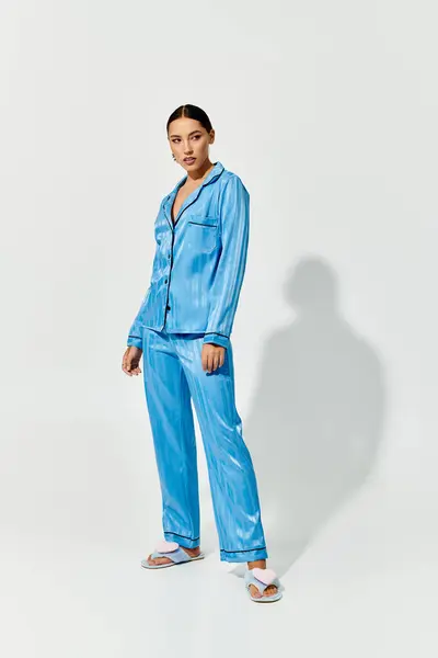A young woman stands confidently in vibrant blue loungewear showcasing her fashion sense. — Stock Photo