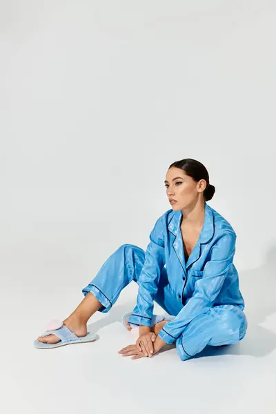 A beautiful young woman sits gracefully, showcasing her chic loungewear in a serene environment. — Stock Photo