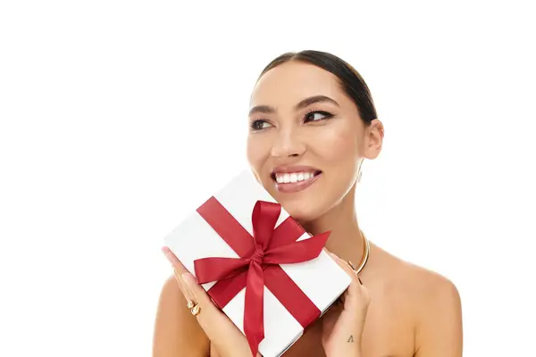 A young woman smiles radiantly while holding a luxurious gift wrapped with a bright bow. — Stock Photo