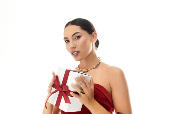 The stunning woman with dark hair is showcasing a festive gift while posing elegantly. — Stock Photo