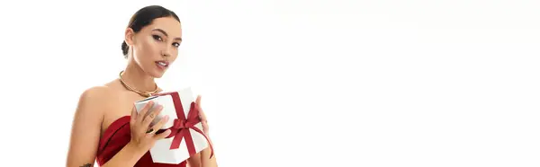A joyful young woman showcases a carefully wrapped gift, radiating happiness and charm. — Stock Photo