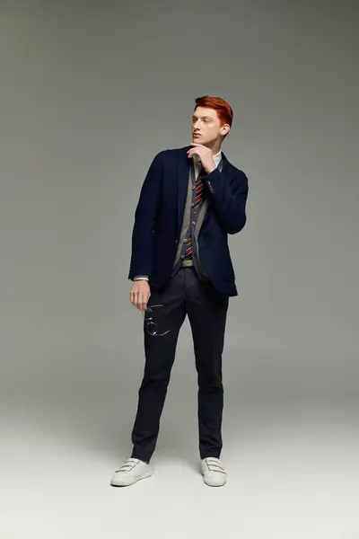 A handsome young man with red hair showcases a sophisticated winter look while striking a thoughtful pose. — Stock Photo