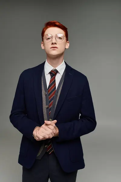 A young man with striking red hair showcases his elegant layered winter outfit while posing in a studio. — Stock Photo