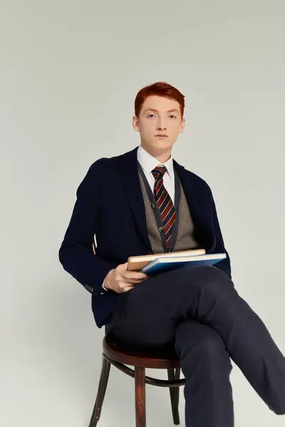 A poised young man with striking red hair showcases his fashionable winter outfit while seated gracefully. — Stock Photo