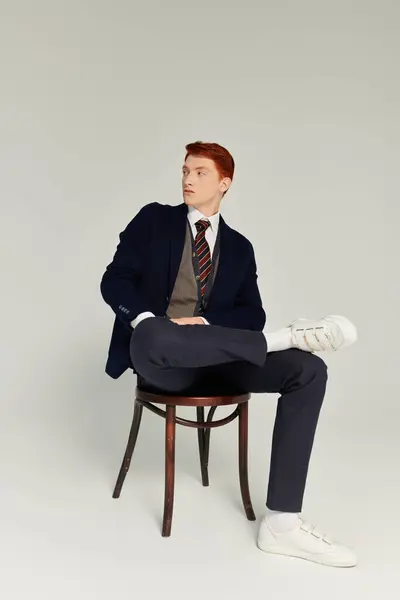 Um jovem estudante com cabelo vermelho impressionante exibe uma roupa de inverno elegante em um ambiente acolhedor estúdio. — Fotografia de Stock