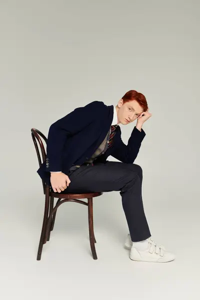 A stylish young man with red hair showcases a trendy winter outfit, exuding confidence in a studio environment. — Stock Photo