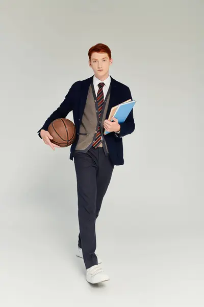 A young man with striking red hair is dressed elegantly in layered winter attire, holding a basketball. — Stock Photo