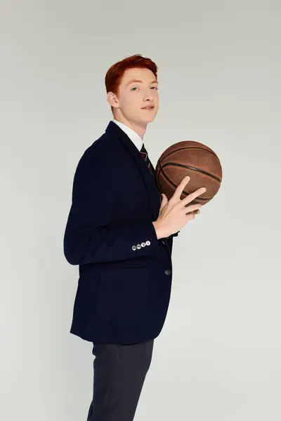 A young man with striking red hair poses confidently in a stylish winter outfit while holding a basketball. — Stock Photo