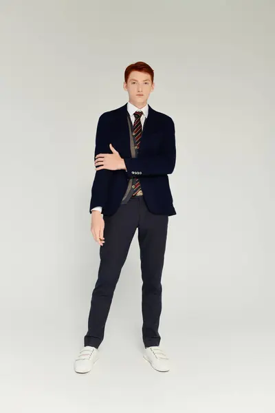 A handsome young student showcases an elegant winter outfit, exuding confidence in a creative studio setting. — Stock Photo