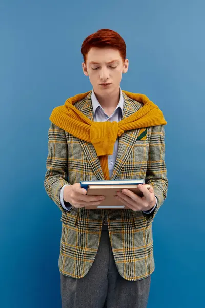 The young man with red hair engages with a book, showcasing an elegant winter outfit that shines. — Stock Photo