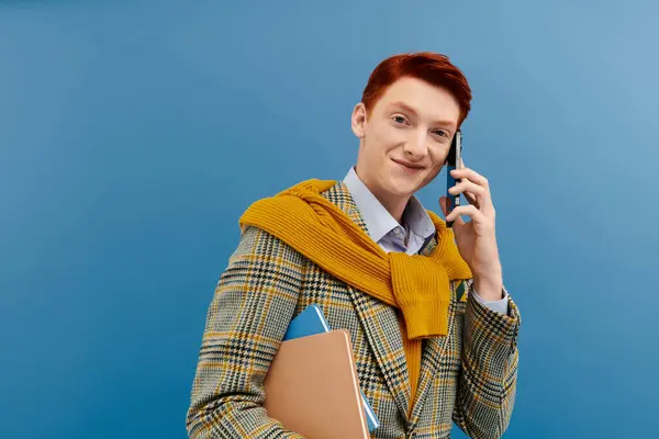 A young man with vibrant red hair smiles while on the phone, dressed elegantly for the winter season. — Stock Photo