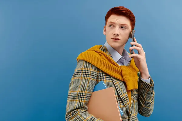A fashionable young man with striking red hair is engaged in a phone conversation while looking stylish. — Stock Photo