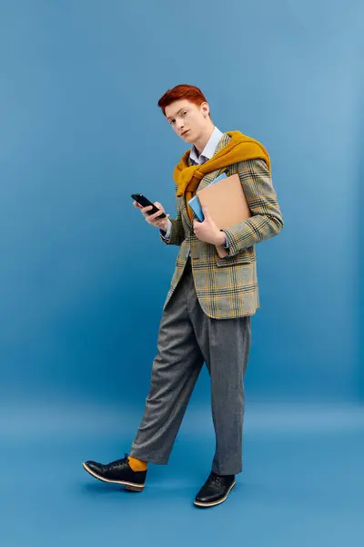 A young student with red hair exudes style in layered winter attire, holding a phone and a notebook. — Stock Photo