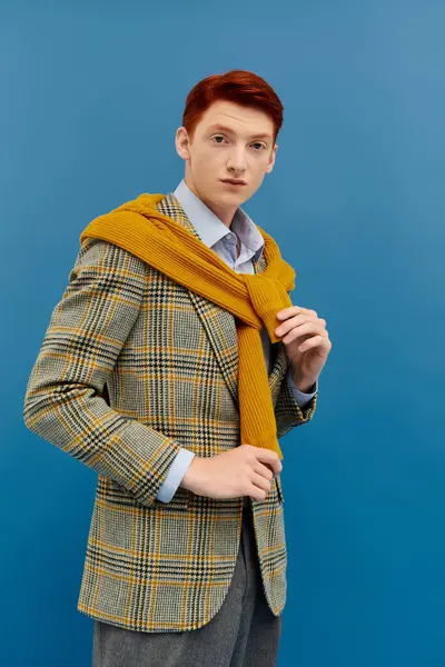 Un giovane uomo con sorprendenti modelli di capelli rossi un abito invernale stratificato, trasudando stile e fiducia in uno studio. — Foto stock