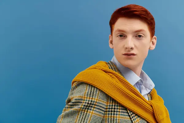 Un hombre elegante con el pelo rojo llamativo muestra un traje en capas de moda en un fondo de estudio. - foto de stock