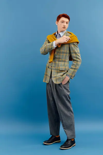 Um jovem elegante posa com confiança, exibindo uma roupa de inverno em camadas chique com um blazer quadriculado. — Fotografia de Stock