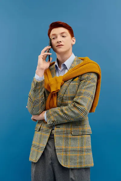 A confident young man in a chic winter outfit captures attention while engaged in a phone call. — Stock Photo