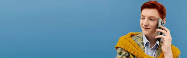 Un joven con estilo habla por teléfono, vestido con un conjunto de invierno en capas sobre un fondo de estudio. - foto de stock