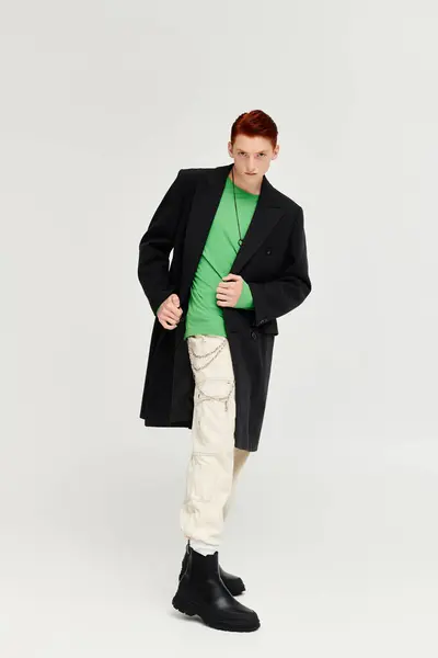 A young man with vibrant red hair models an elegant winter coat in a modern studio environment. — Stock Photo