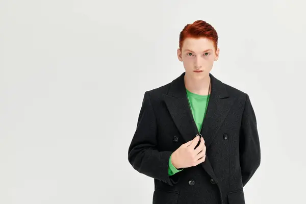 Un jeune homme aux cheveux roux vibrants modèle un élégant manteau d'hiver dans un contexte minimaliste. — Photo de stock