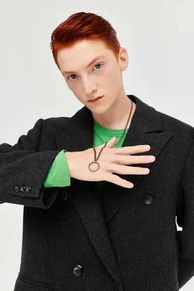 Ein junger Mann mit auffallend roten Haaren posiert selbstbewusst im modischen Wintermantel in einem Atelier. — Stockfoto