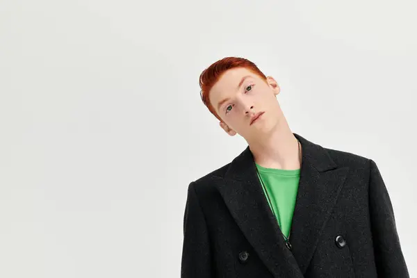 Un uomo elegante con i capelli rossi vibranti posa con fiducia in un elegante cappotto invernale, mettendo in evidenza la moda. — Foto stock