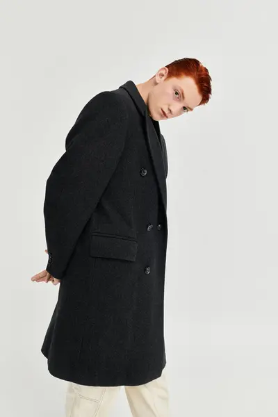 Avancé dans la mode et confiant, un jeune homme présente son style dans un élégant manteau d'hiver. — Photo de stock