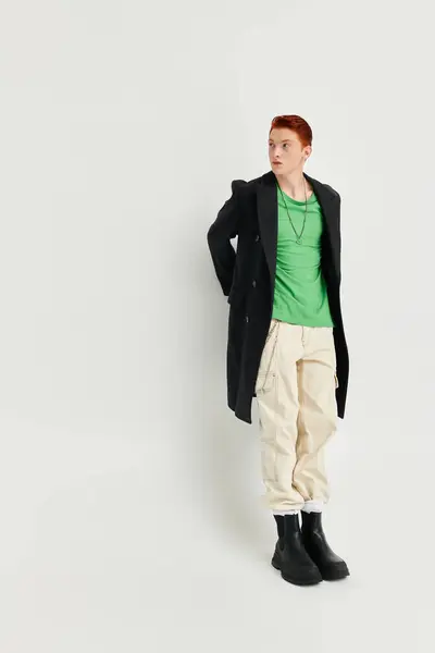A handsome young man with striking red hair showcases his winter fashion in a studio setting, exuding confidence. — Stock Photo