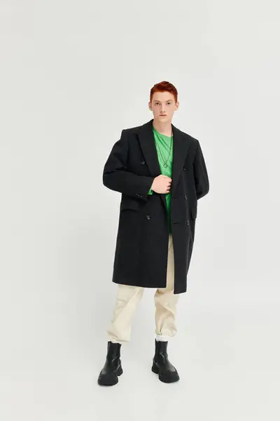 A confident man in an elegant winter coat stands tall against a plain backdrop, exuding fashion finesse. — Stock Photo