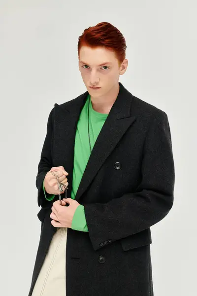 Un jeune homme à la mode aux cheveux roux saisissants pose avec confiance dans un manteau d'hiver élégant à l'intérieur. — Photo de stock