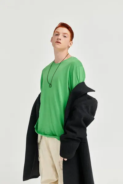 Un jeune homme aux cheveux roux saisissants met en valeur son manteau d'hiver et son haut vert vif dans une atmosphère studio élégante. — Photo de stock