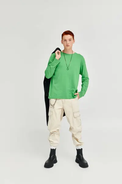 A stylish young man in green long sleeve poses confidently against a neutral backdrop. — Stock Photo