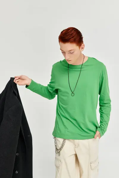A fashionable young man with striking red hair models a chic winter coat in a stylish studio setting. — Stock Photo