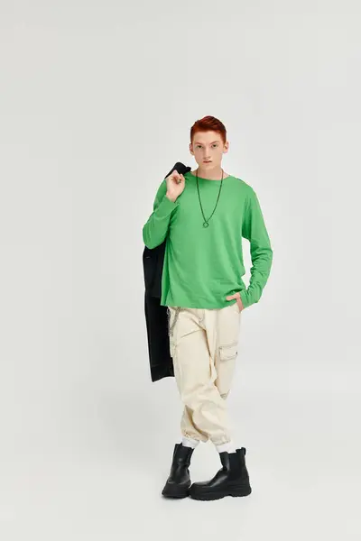 A young, handsome man poses confidently in a studio, dressed in an elegant winter coat and vibrant colors. — Stock Photo