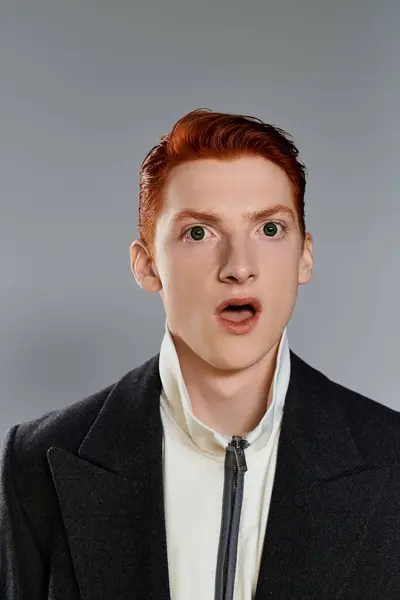 The young man in a stylish winter coat shows an astonished expression, perfectly framed by the neutral background. — Stock Photo