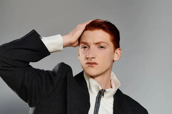 A red-haired man shows off his winter coat style while posing thoughtfully against a grey background. — Stock Photo