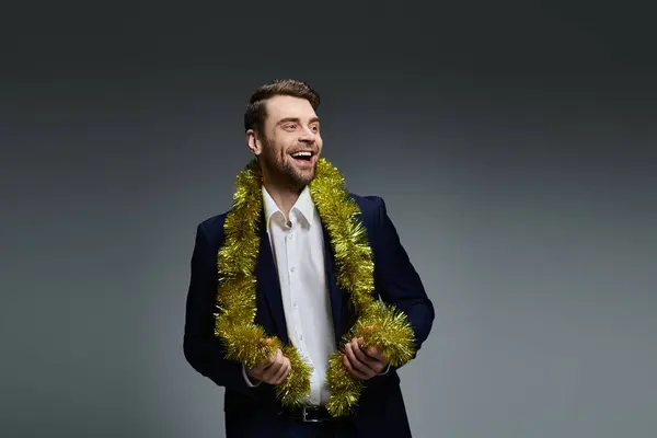 A happy young man in formal attire enjoys a celebration with shiny decorations around his neck. — Stock Photo